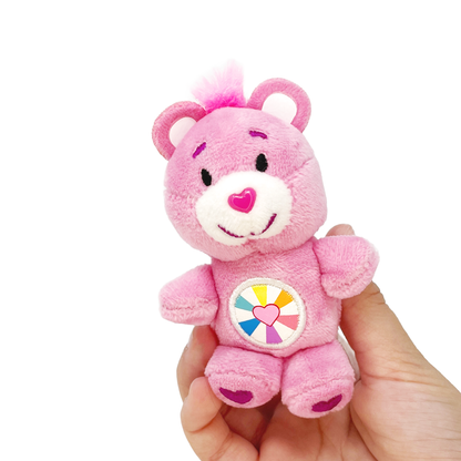 A hand holds a pink Hopeful Heart small Care Bear toy