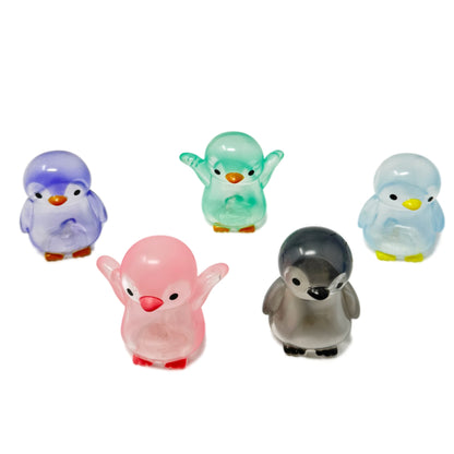 Five translucent penguin gachapon toys including green, purple, pink, grey, and light blue.