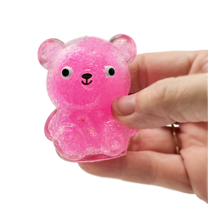 A hand holding a Squish Sticky Glitter Bear.