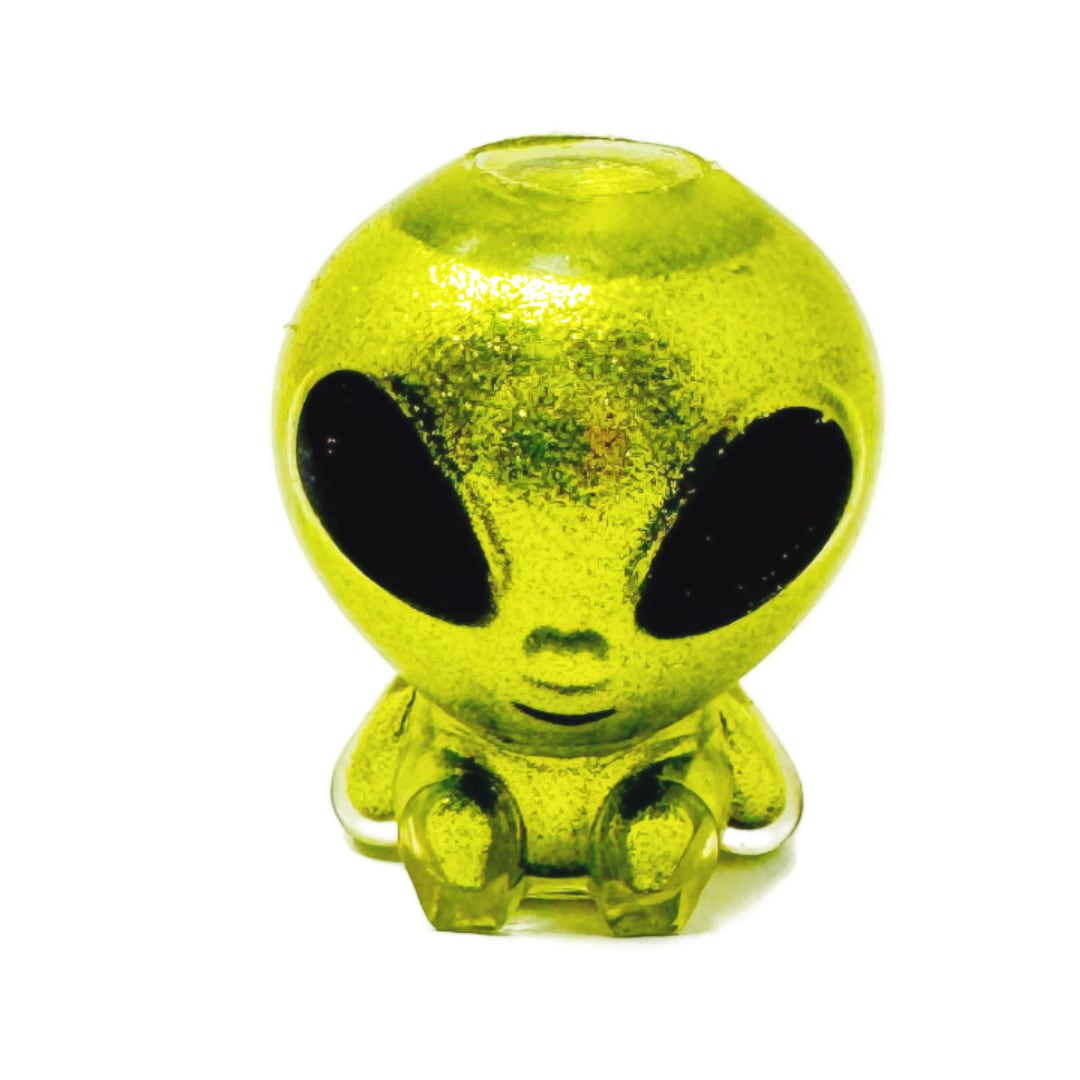 A small squishy toy alien with glittery green skin and big black eyes.