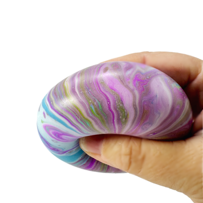 A hand is squeezing a blue and purple marbled stress ball fidget toy.