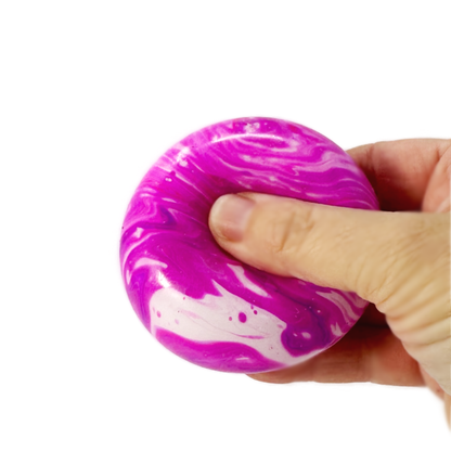 A hand is squeezing a marbled stress ball fidget toy.