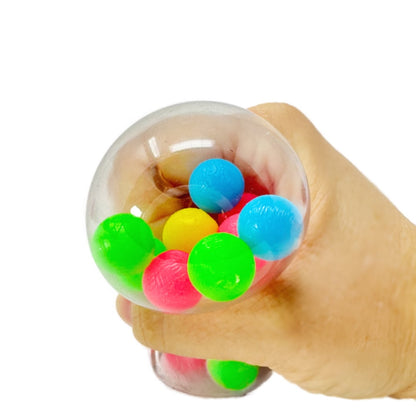 A hand squeezing a squishy clear toy ball with smaller colorful balls inside.