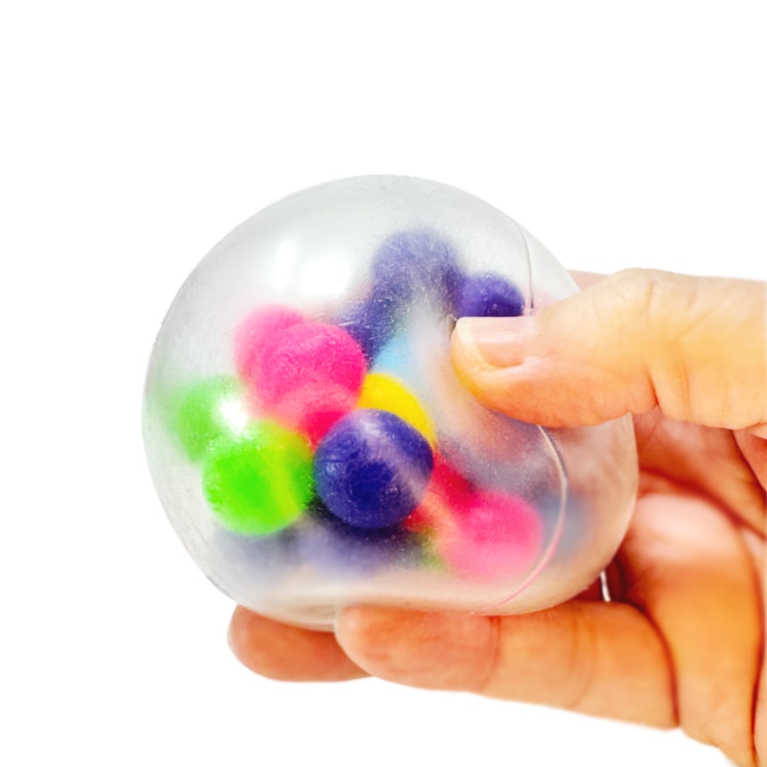 A hand holding a squeezy toy ball with smaller colorful balls inside.