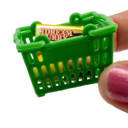 Fingers hold a tiny green shopping basket with mini collectible play food.