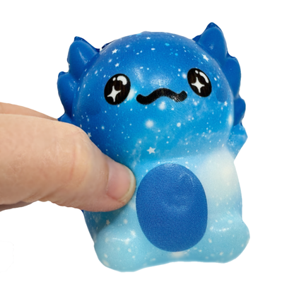 A hand holds a blue galaxy axolotl squish toy with star eyes.