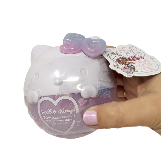 A hand holds a Hello Kitty 50th Anniversary themed L.O.L. Surprise doll ball.