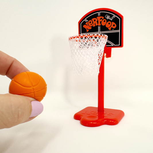 Fingers hold a squishy Nerf basketball while taking a shot at the Nerfoop mini desk sized hoop.