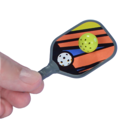 A hand holds a tiny pickleball paddle hitting a pickle ball.