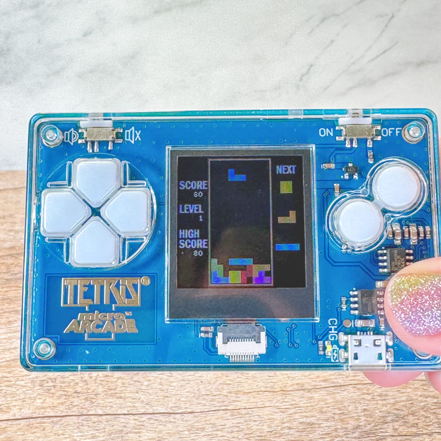 A hand holds the Micro Tetris Arcade but the player has made some mistakes.