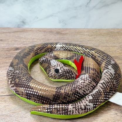 A sand filled toy snake lays coiled on a table.