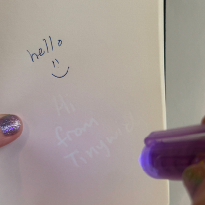 'Hello" is written in ink by the Invisible Writer Pen while the pen's light shows a secret message " Hi from Tinywich"