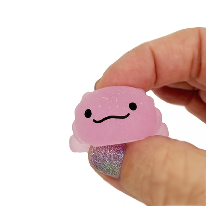 Fingers squish a pink gummy axolotl toy