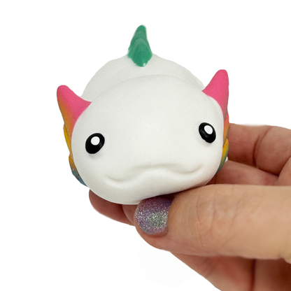 A hand holds a white sand axolotl stress toy