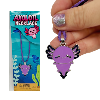 A hand holds the purple axolotl necklace. Behind it is the necklace in the packaging