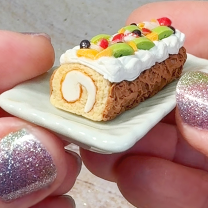 Hands hold a miniature cake roll on a porcelain plate