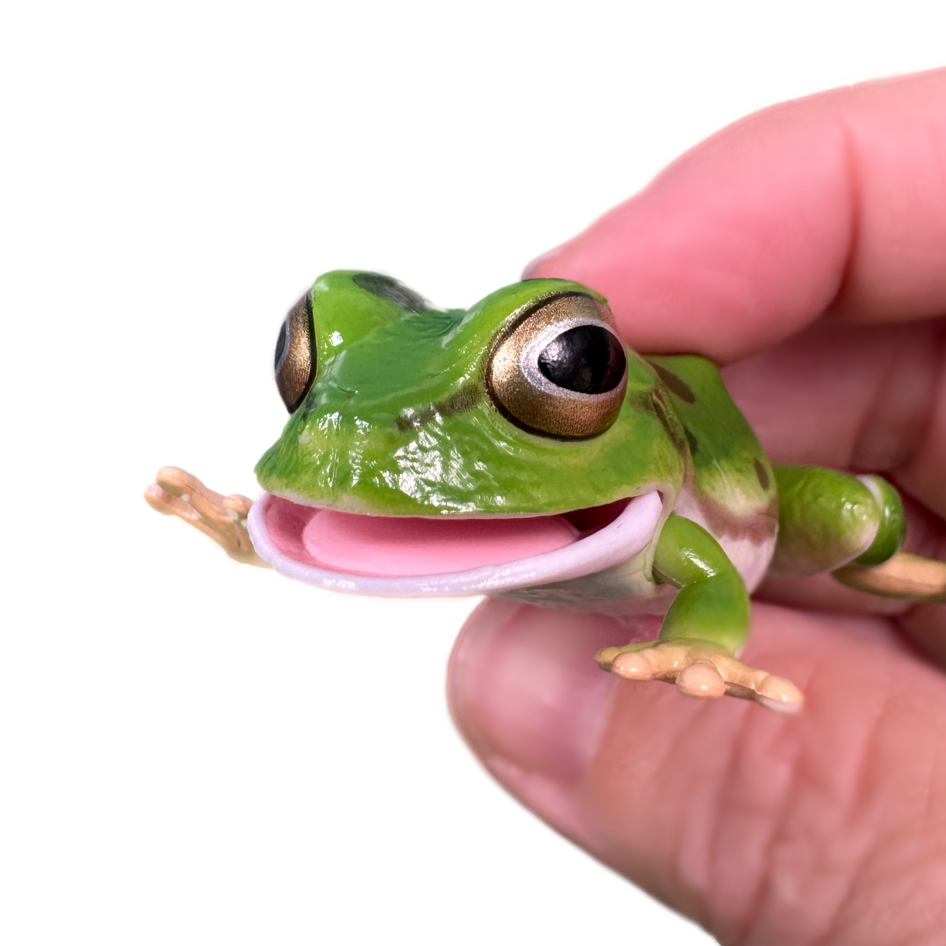 A hand holds a green toy tree frog with spots and movable parts.