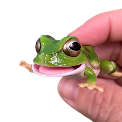 A hand holds a green toy tree frog with spots and movable parts.