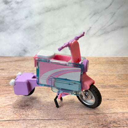 The pastel pink and purple toy tatamel bike shown unfolded.