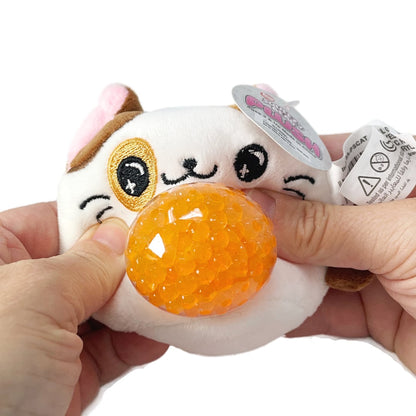 Two hands holding  a white toy cat sensory plush toy with a squeezable orange bead tummy.