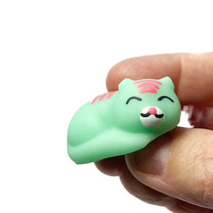 A hand holds a small toy cat squishy fidget. 