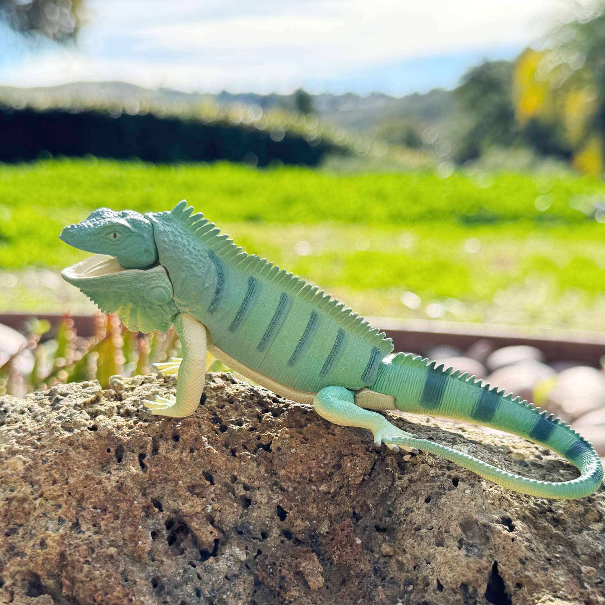 An iguana toy playable lizard sitting on a rock in nature